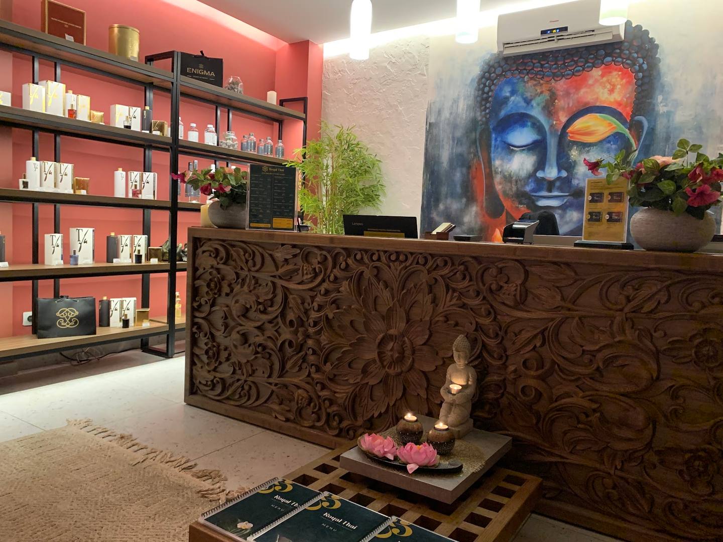 Spa reception area with ornate wood counter, colorful shelving, and wellness artwork