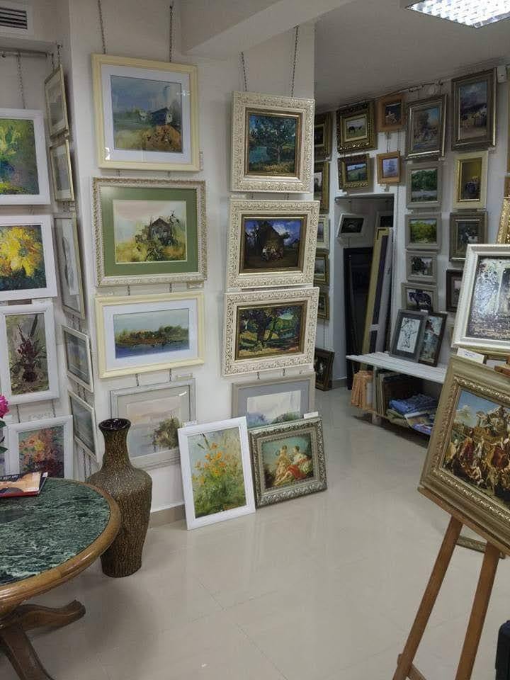 Art gallery studio space displaying framed landscape paintings and artwork displays