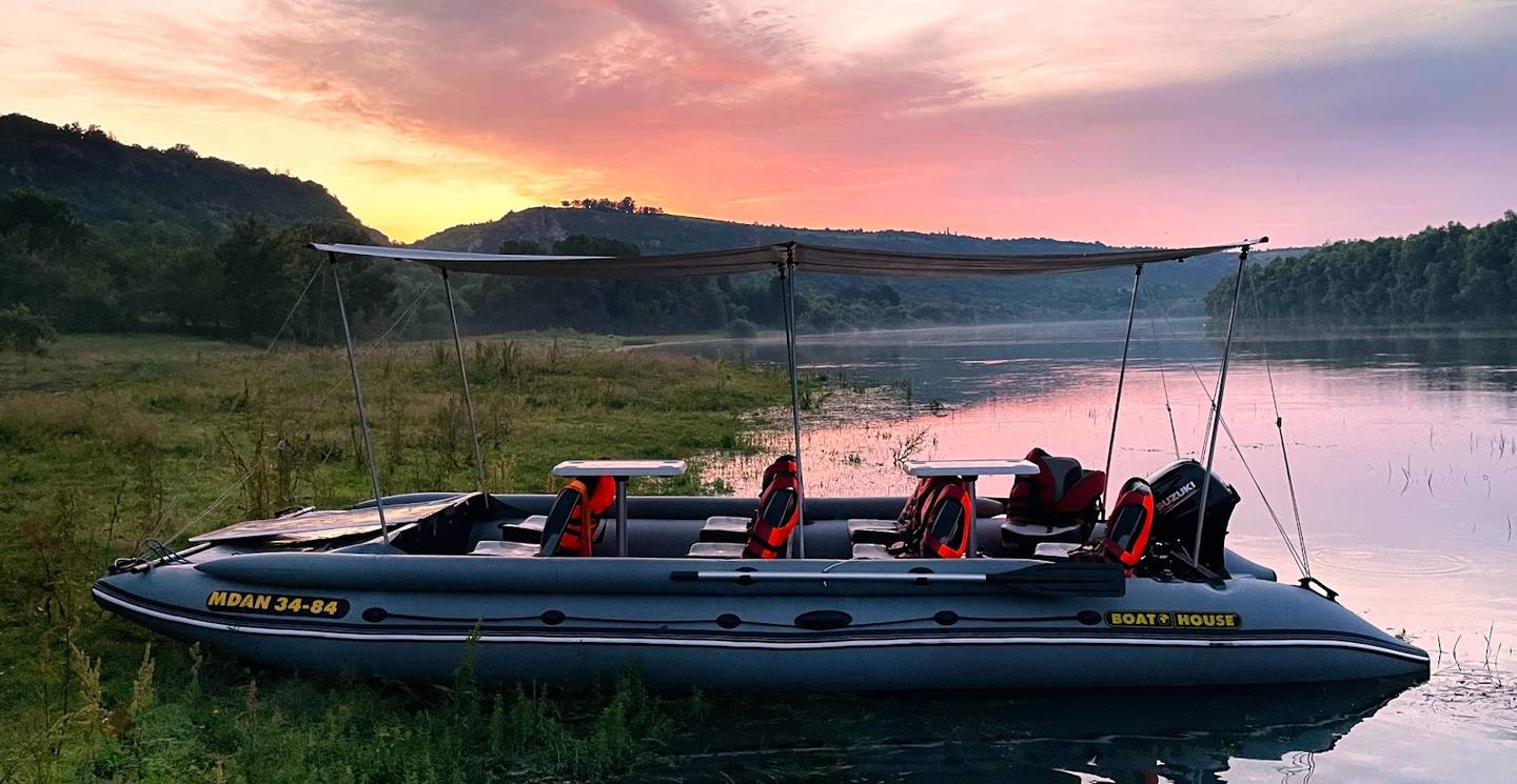 Speedboat moored on calm river at sunrise with forested landscape