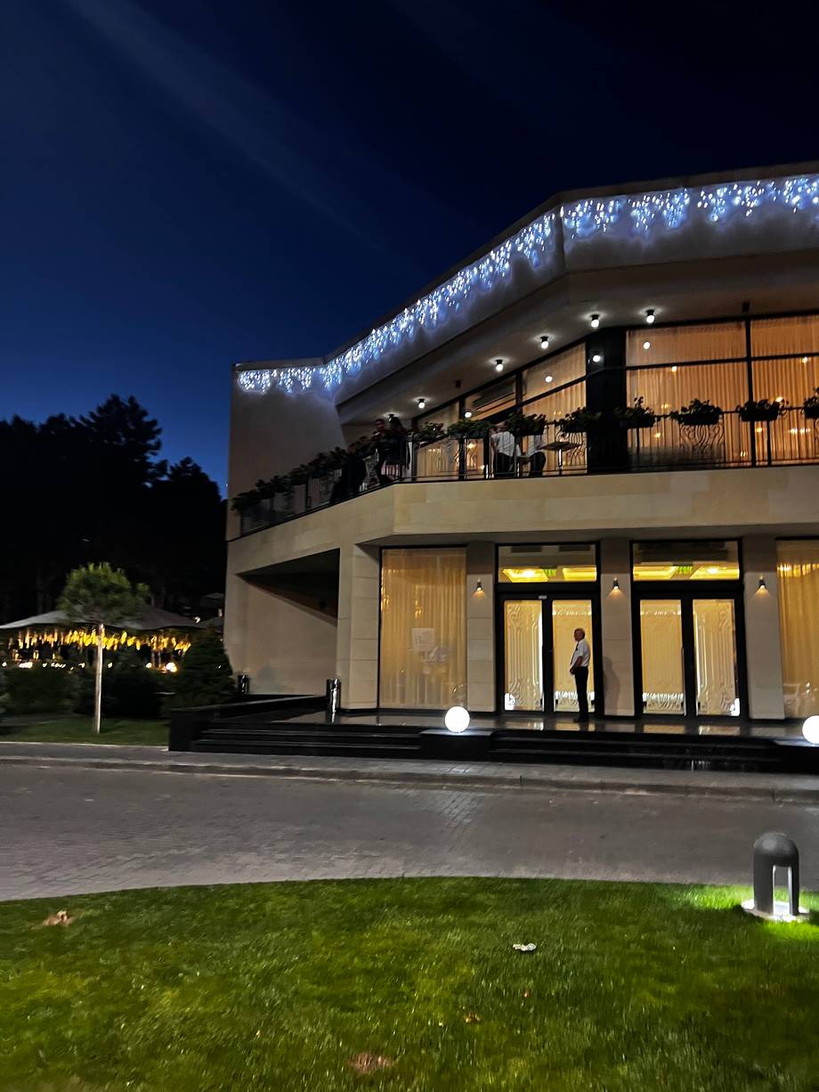 Modern curved glass façade event venue at night with illuminated architecture and landscaped grounds