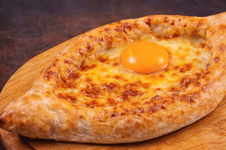 Khachapuri with egg yolk on wooden serving board