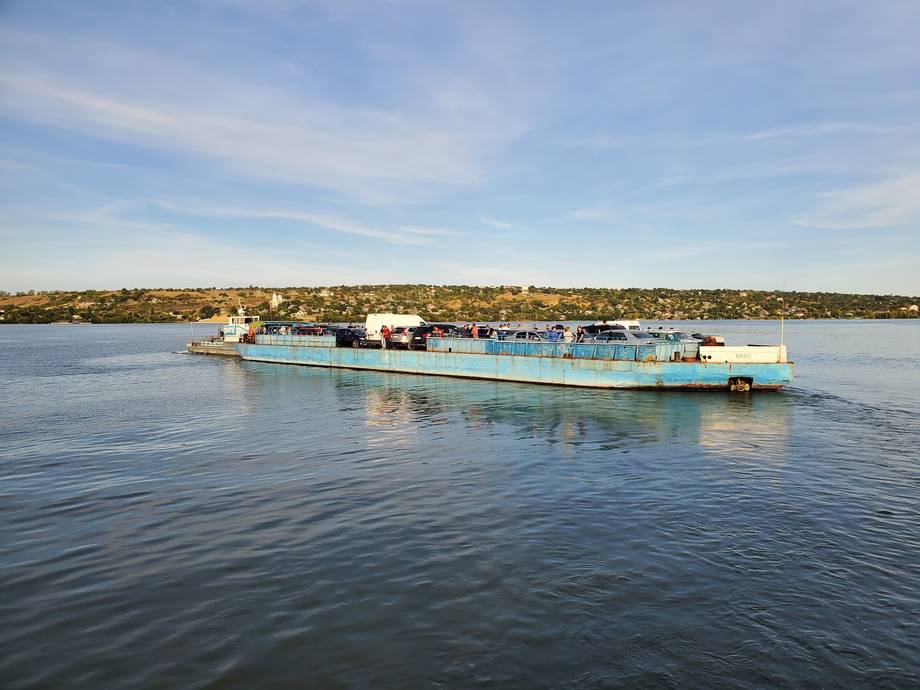River cruise boat on calm waterway with coastal town in background