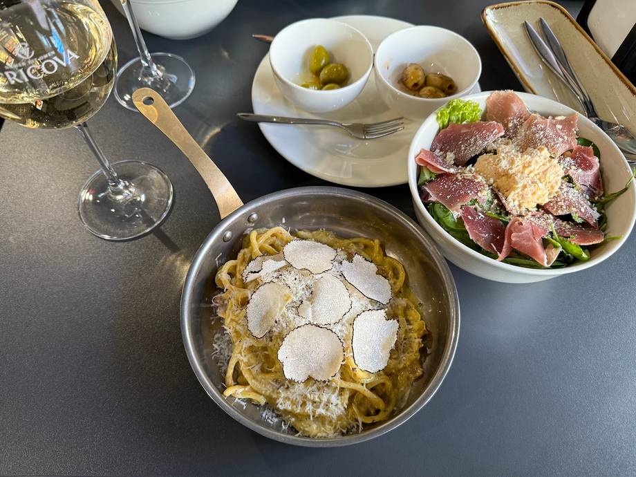 Plated pasta dishes with wine and appetizers on a dark table