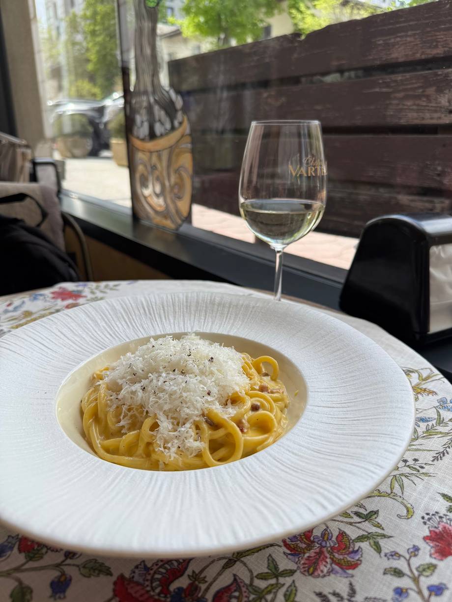 Creamy pasta dish with grated cheese and wine service on terrace