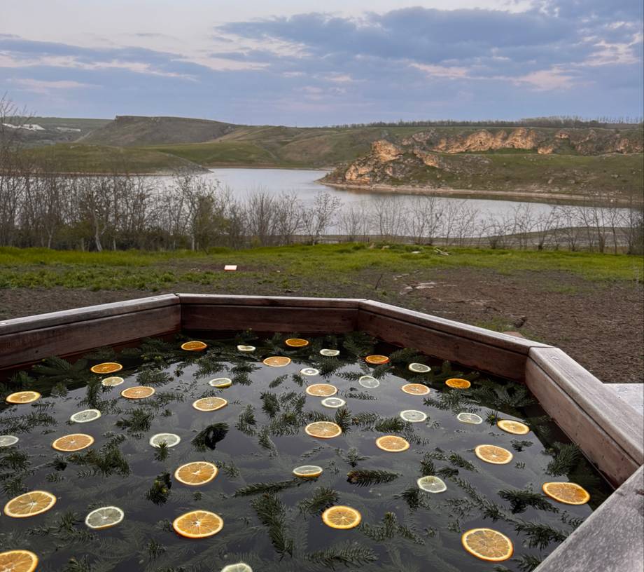 Outdoor wellness bath with citrus-infused water overlooking river landscape