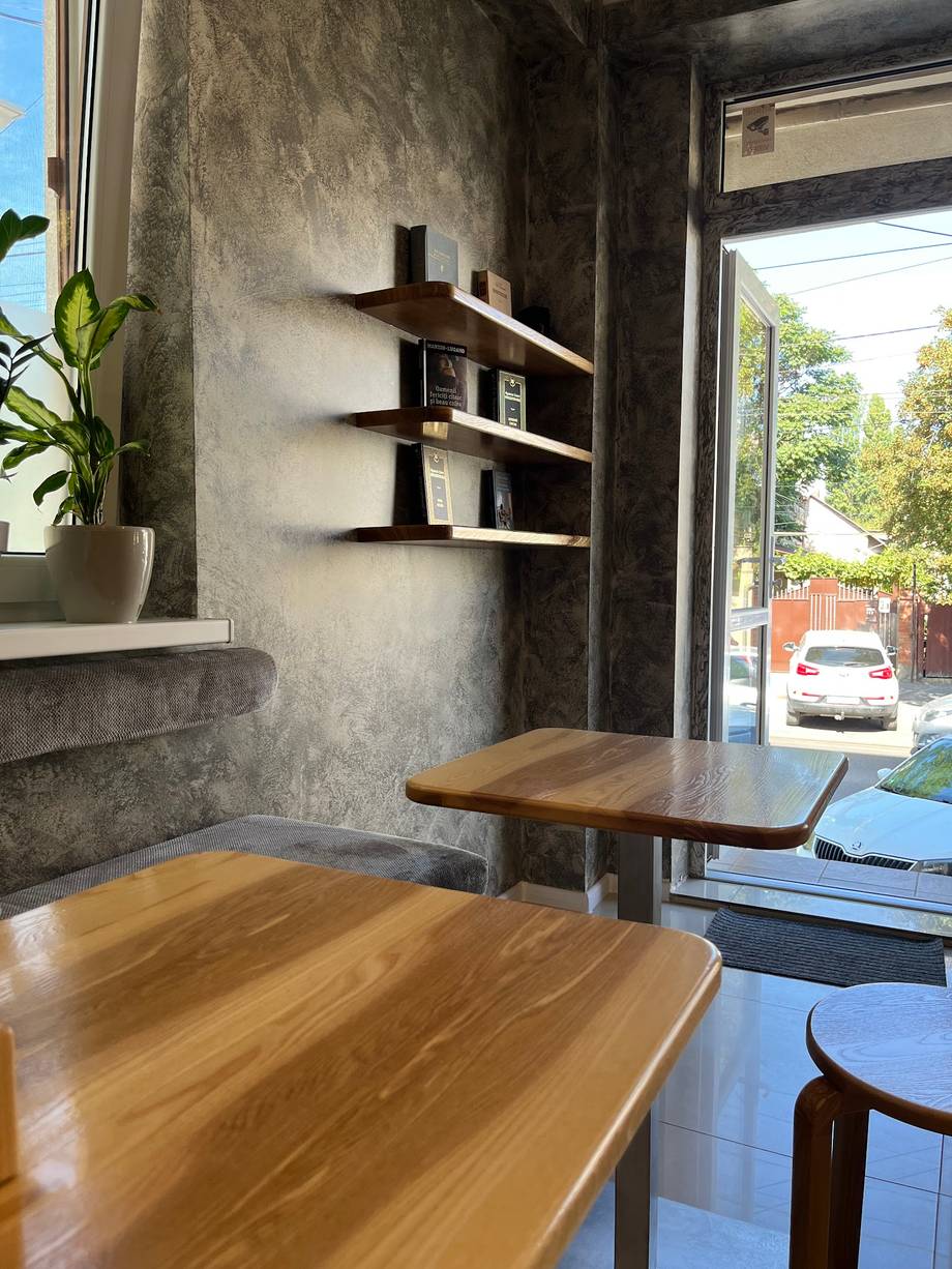 Modern café interior with wooden tables, concrete walls, and street-facing storefront view