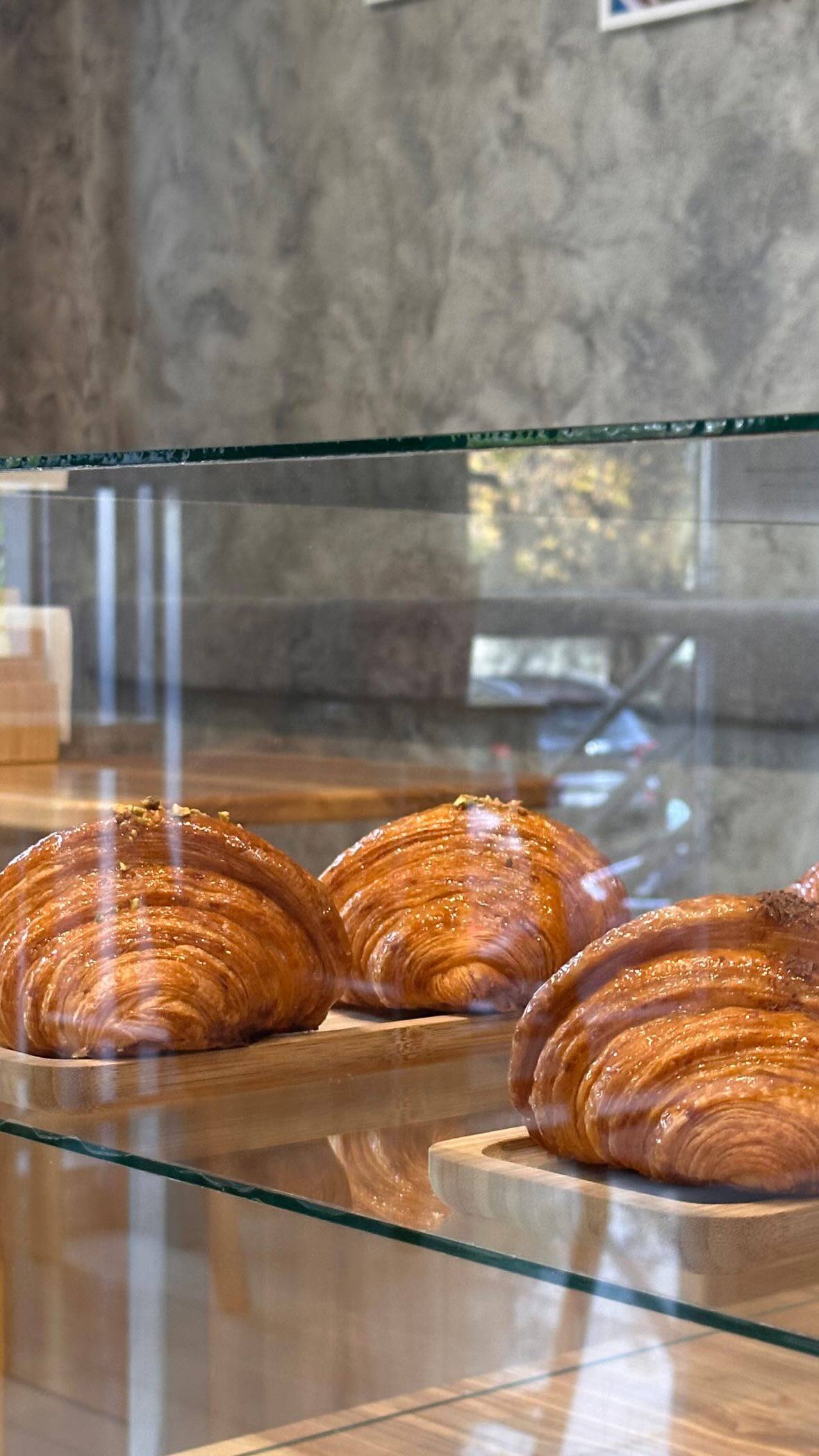 Artisan croissants displayed in bakery case with modern interior