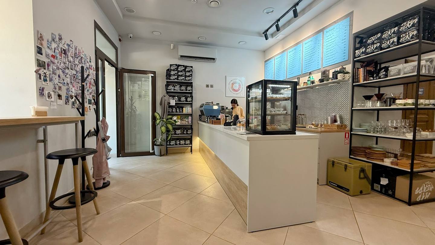 Modern cafe counter with white L-shaped bar, display shelving, and natural light