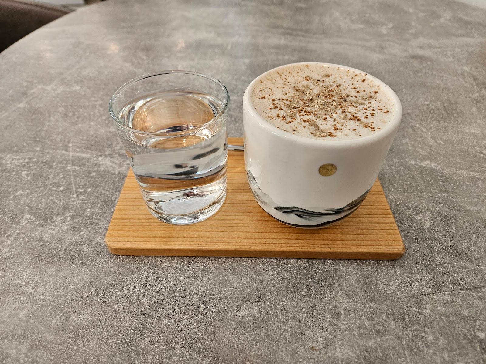 Cappuccino with water service on wooden board