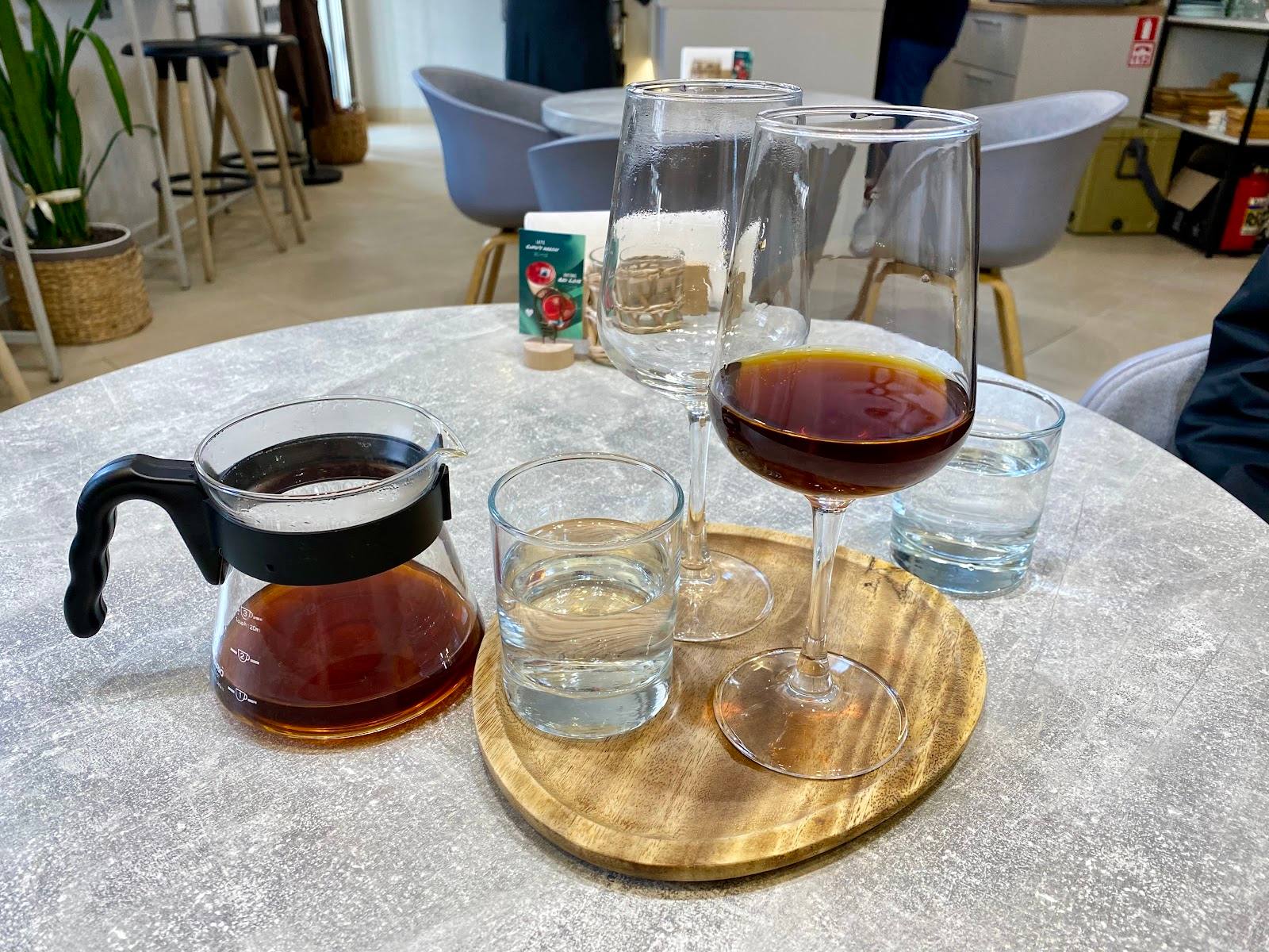 Coffee tasting setup with carafes, glasses, and wooden serving board