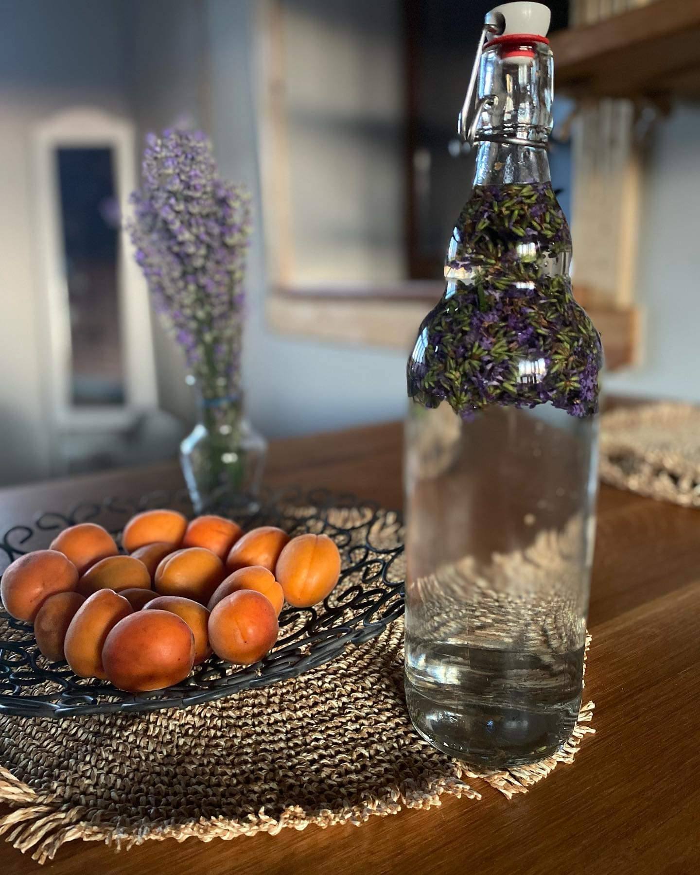 Herbal-infused bottle with fresh fruit and lavender styling on rustic table setting