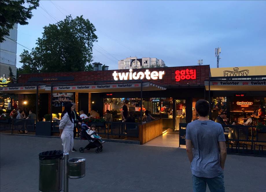 Twister bar exterior storefront with illuminated signage and crowd during evening hours