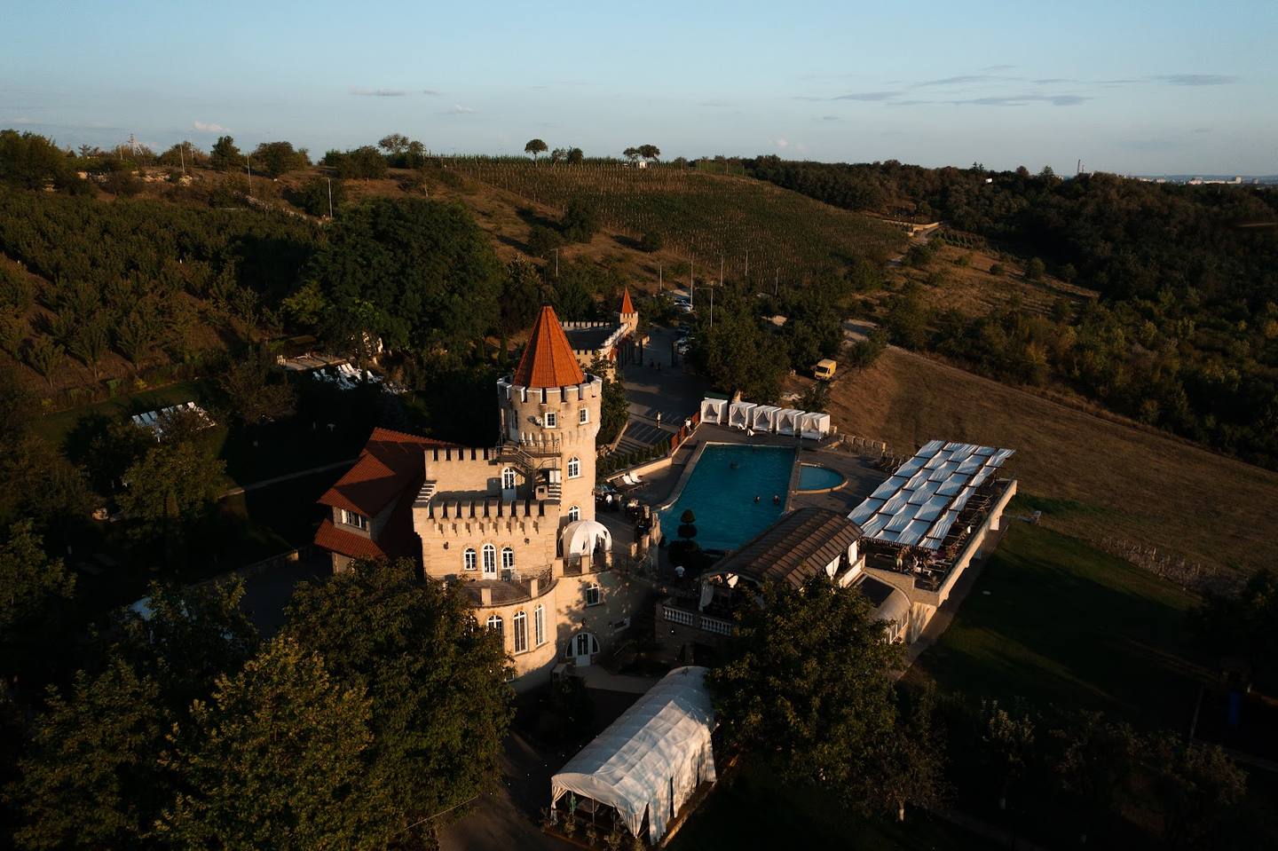 Aerial view of castle with turrets, pool, and event grounds in countryside setting