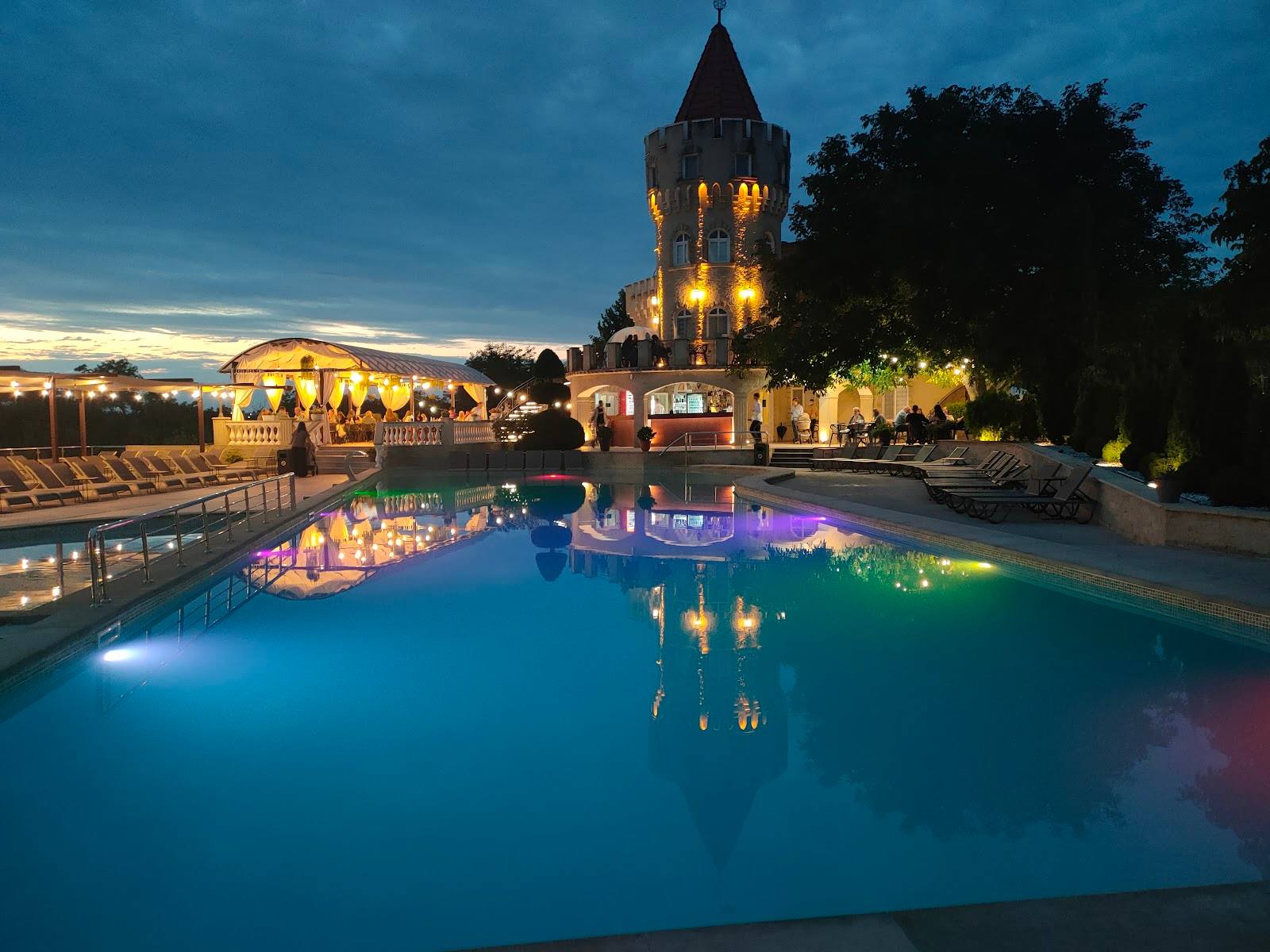 Illuminated castle tower reflected in glowing pool at twilight