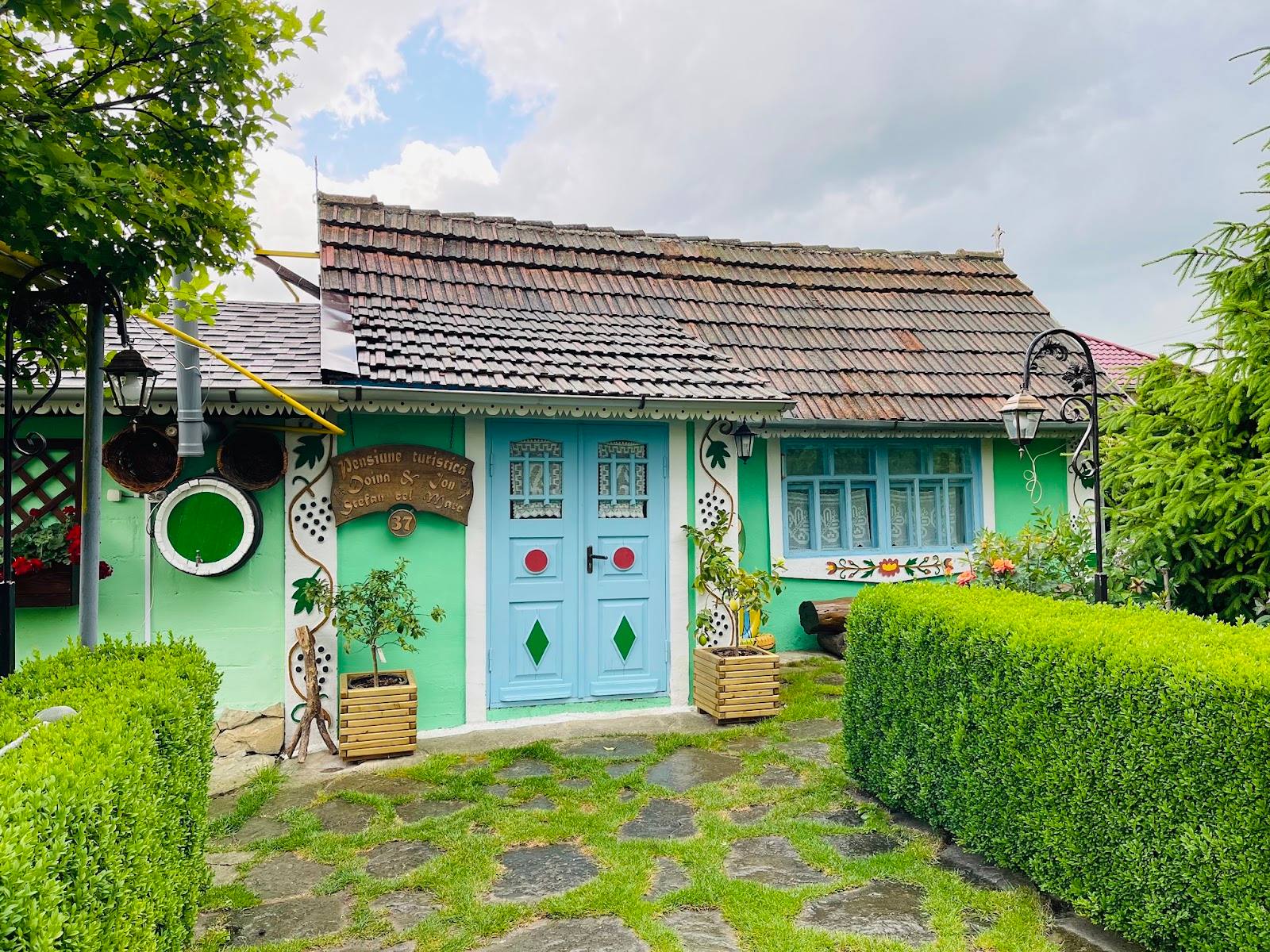 Charming mint-green cottage with traditional tile roof and manicured hedges