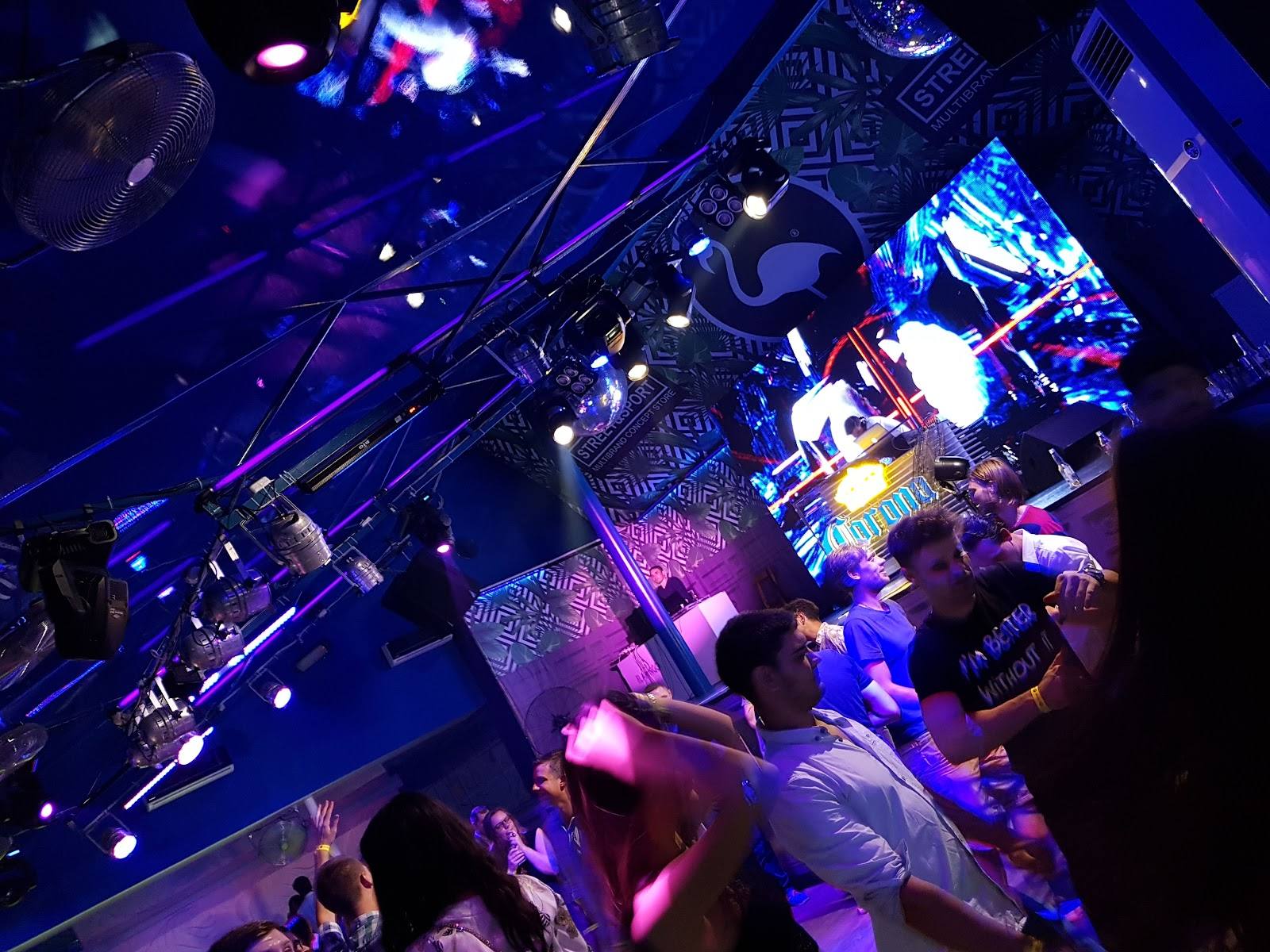 Live band performing on stage with purple and blue lighting in nightclub setting