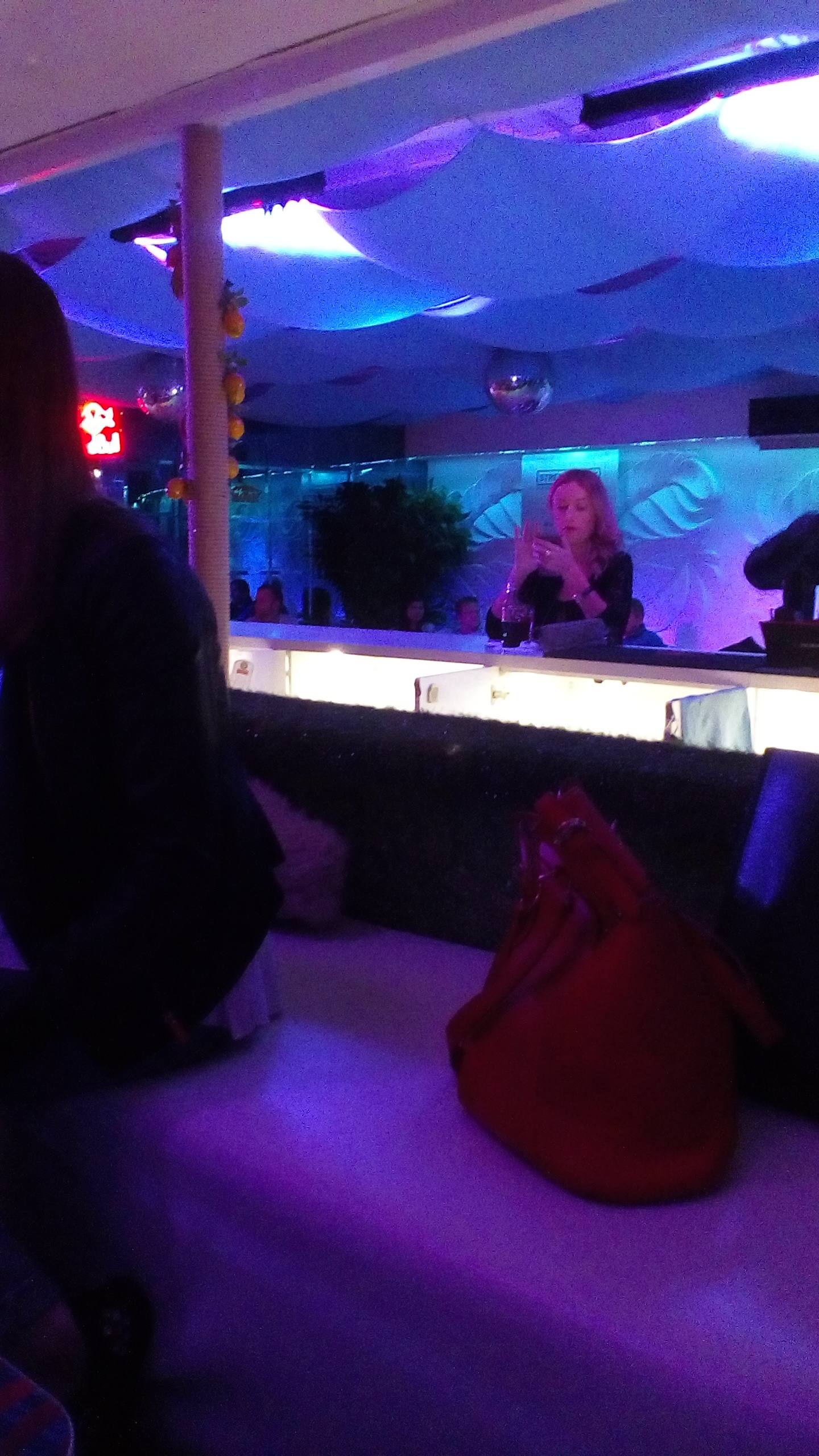 Nightclub bar counter with blue and purple ambient lighting and DJ booth