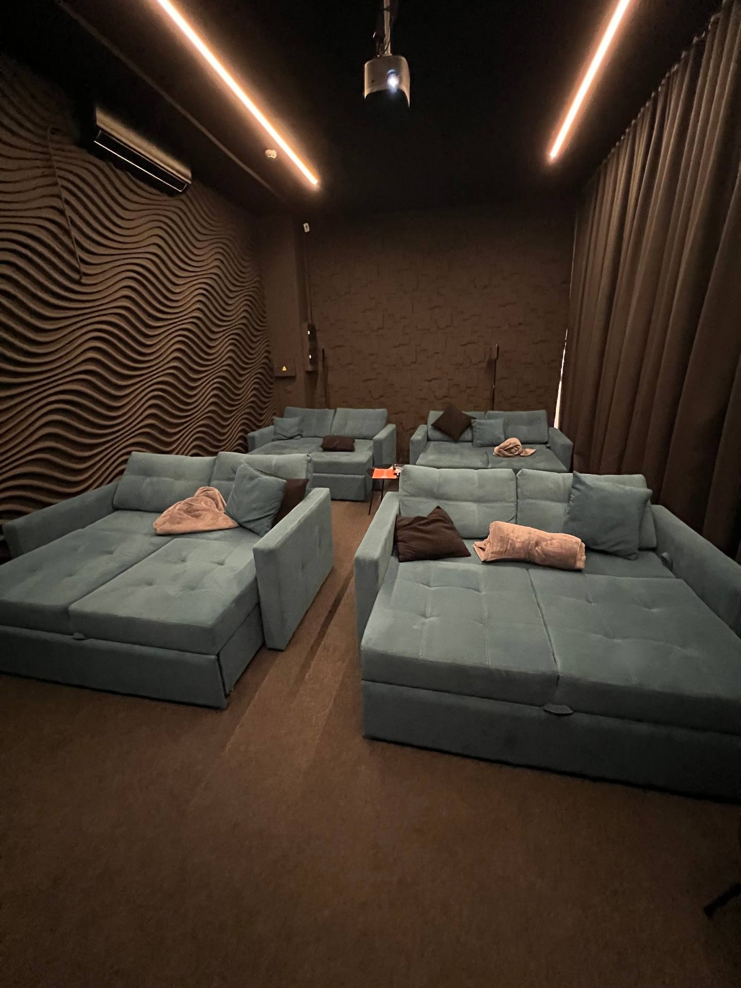 Cinema lounge with modular seating, ambient lighting, and wavy acoustic panels
