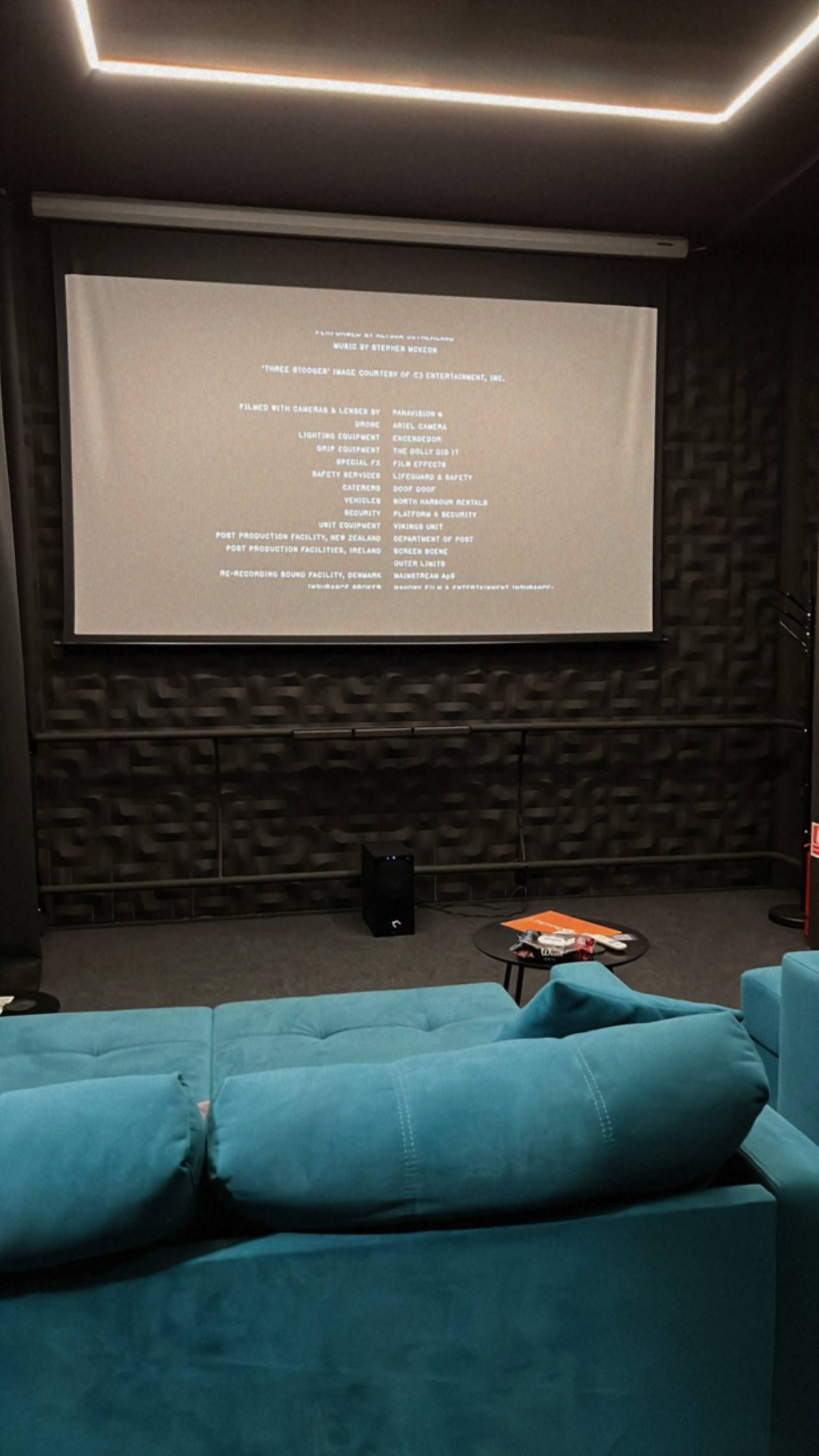 Home cinema room with projection screen and turquoise seating