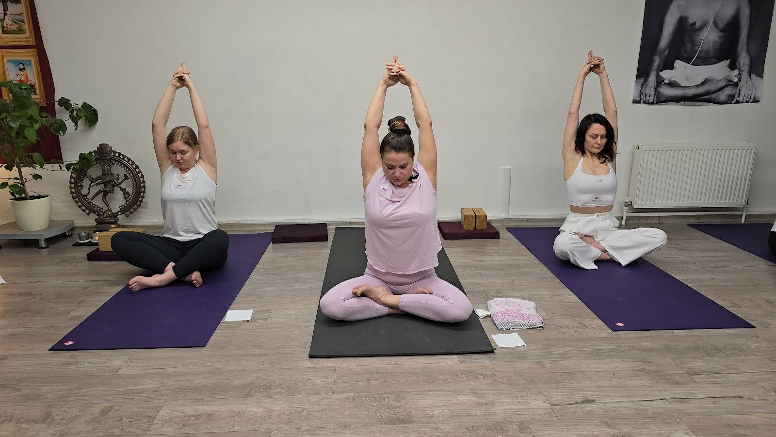 Yoga class in session with three participants on mats in a light, airy studio