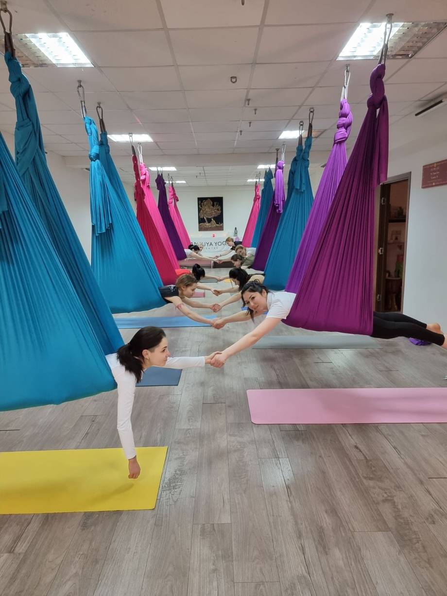 Aerial yoga class in progress with colorful suspended fabric hammocks