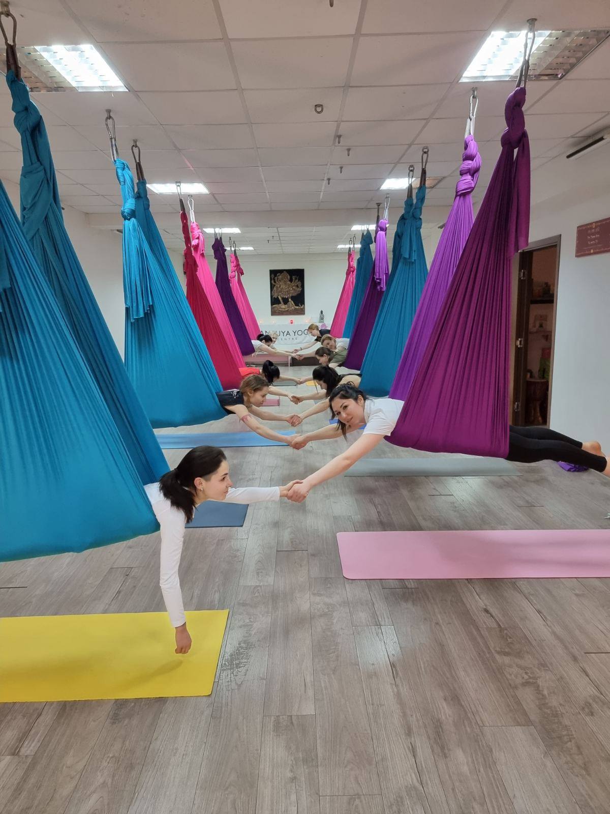 Aerial yoga class in progress with colorful suspended fabric hammocks