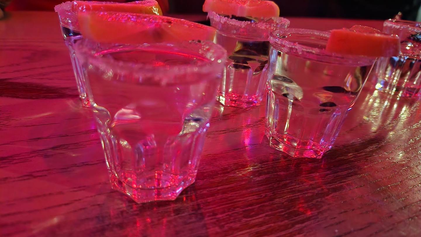Colorful cocktail glasses with pink lighting on a bar surface