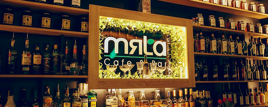 Mala bar illuminated sign with extensive bottle collection on wooden shelves