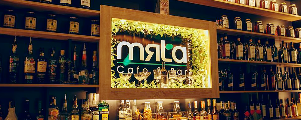 Mala bar illuminated sign with extensive bottle collection on wooden shelves