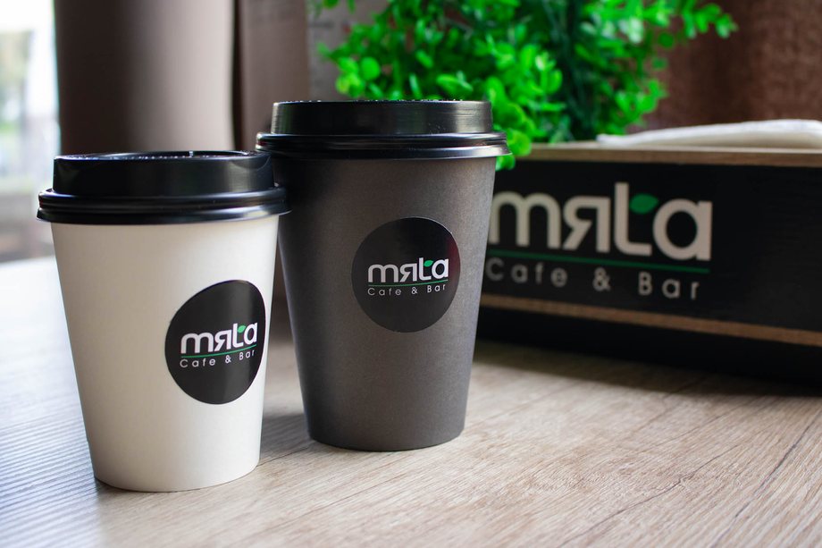 Mala Cafe & Bar branded coffee cups on wooden counter