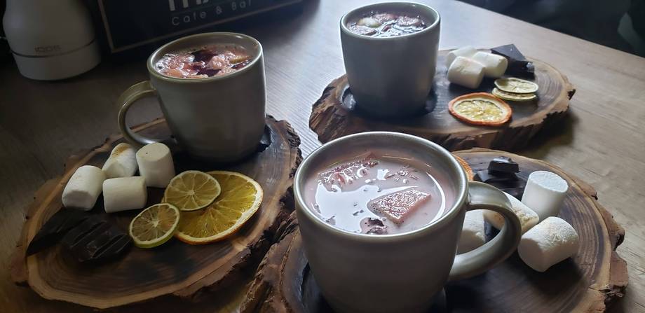 Hot beverages with citrus garnish and marshmallows on rustic wooden boards