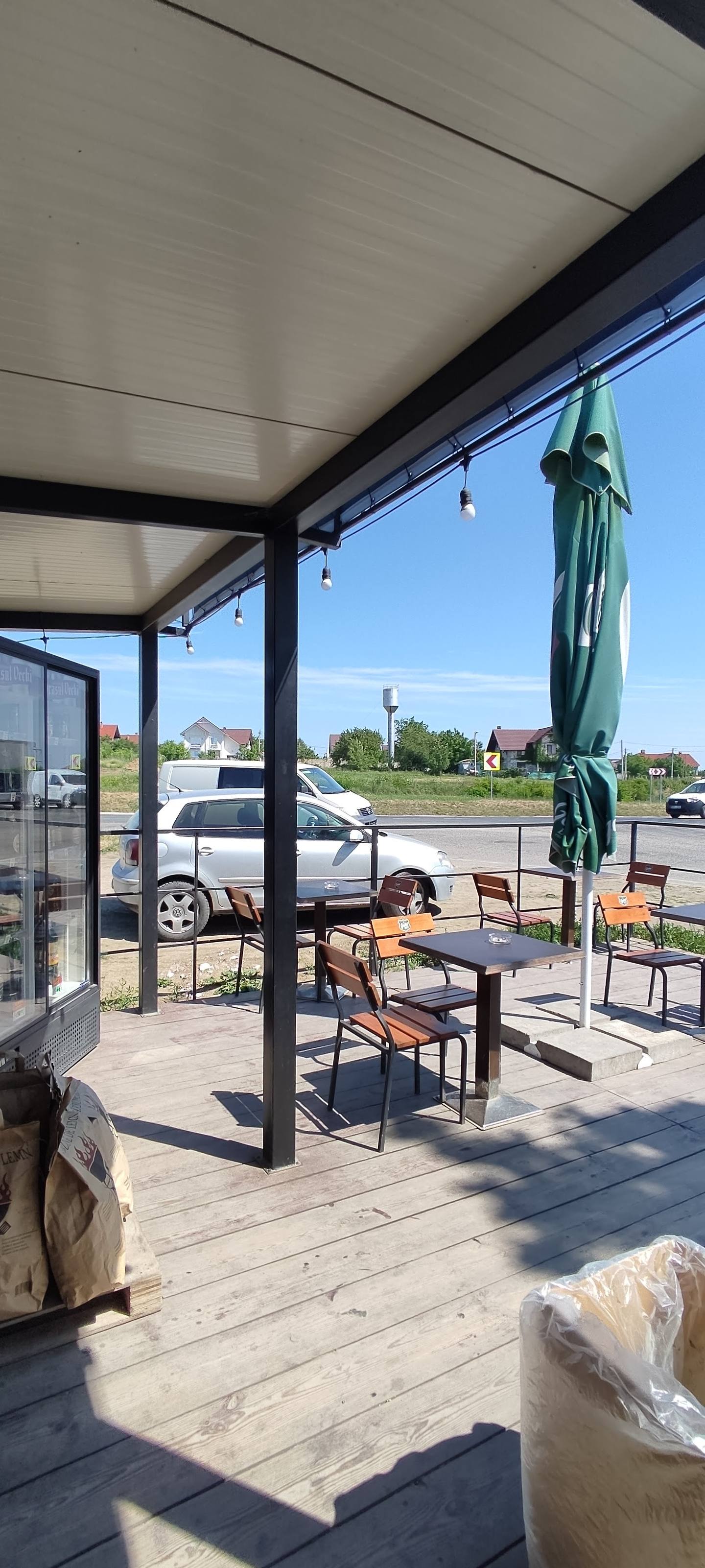 Bright outdoor terrace with pergola seating overlooking parking lot and countryside