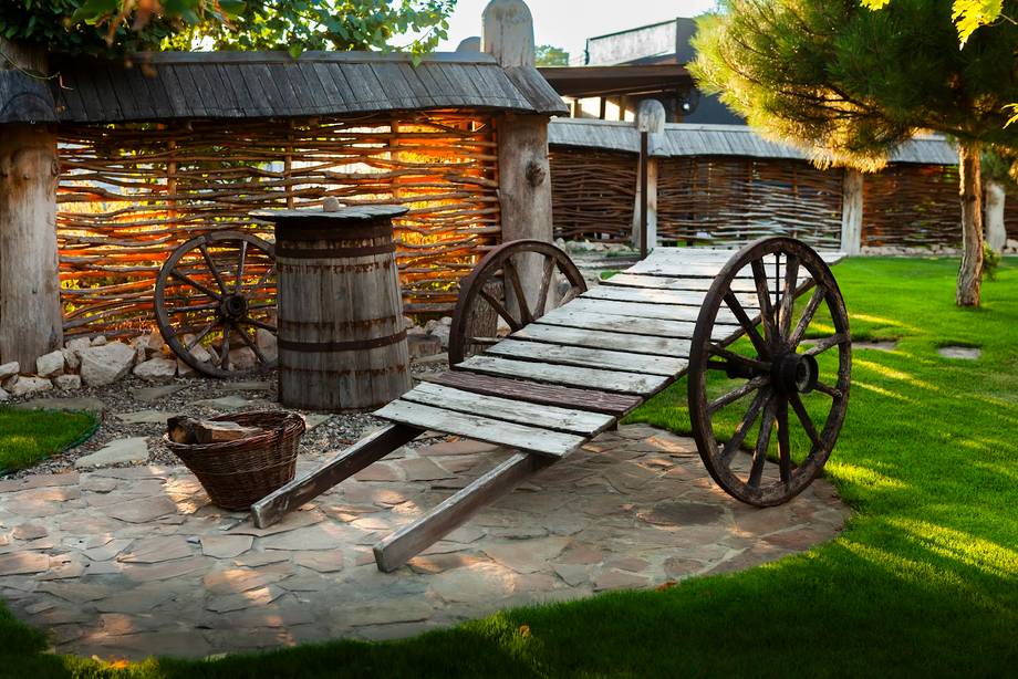 Historic wooden cart and traditional stone buildings at rural monastery grounds