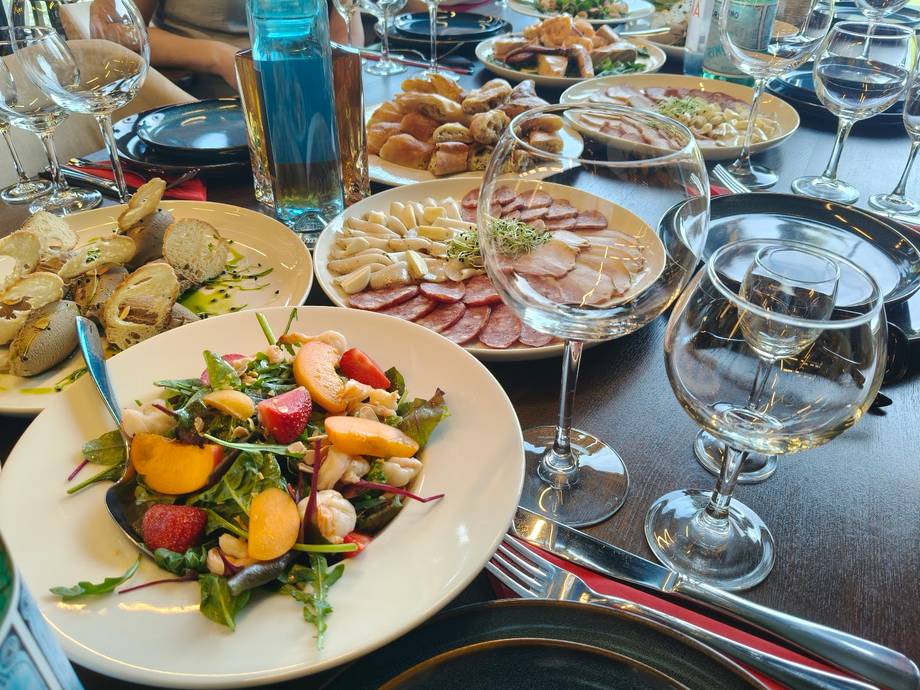 Restaurant table spread with fresh salad, charcuterie, baked goods and wine service