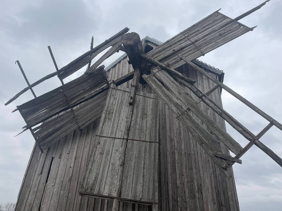 Wooden windmill with traditional cross-beam sails against overcast sky