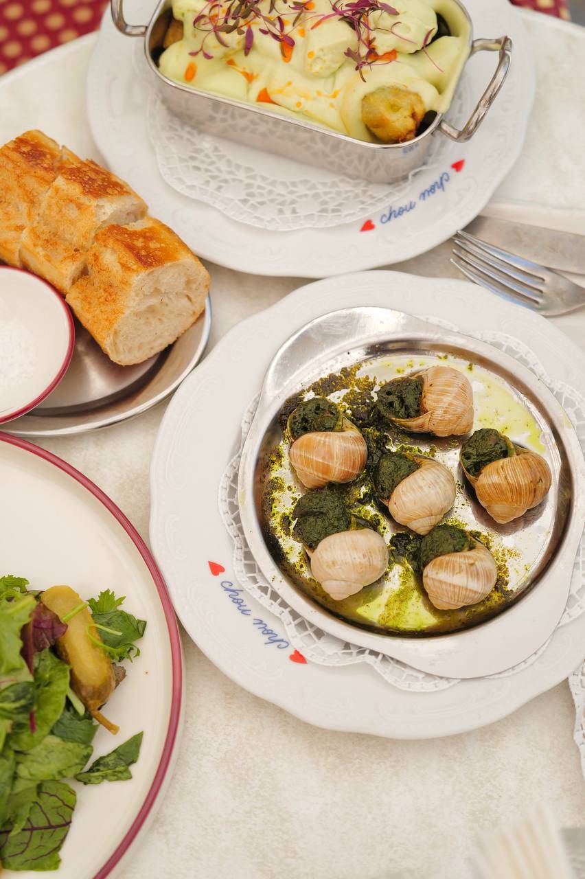 Table spread with scallops in greens sauce, roasted bread, and potato dish at fine dining restaurant