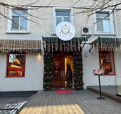 Restaurant storefront with white facade, decorated entrance with ivy garland and illuminated signage
