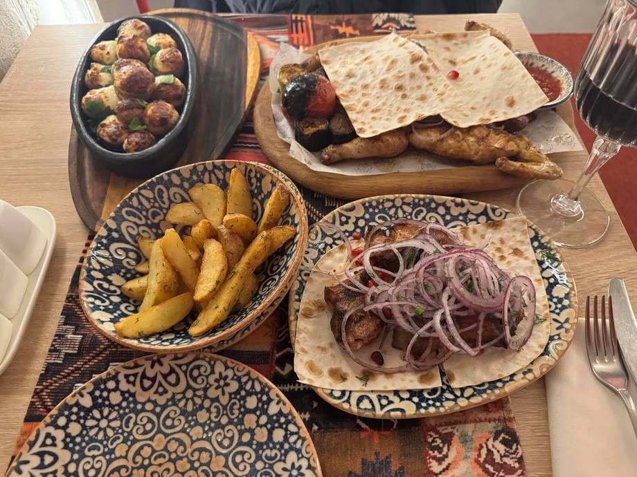 Table spread of grilled meat, fries, and traditional appetizers at restaurant