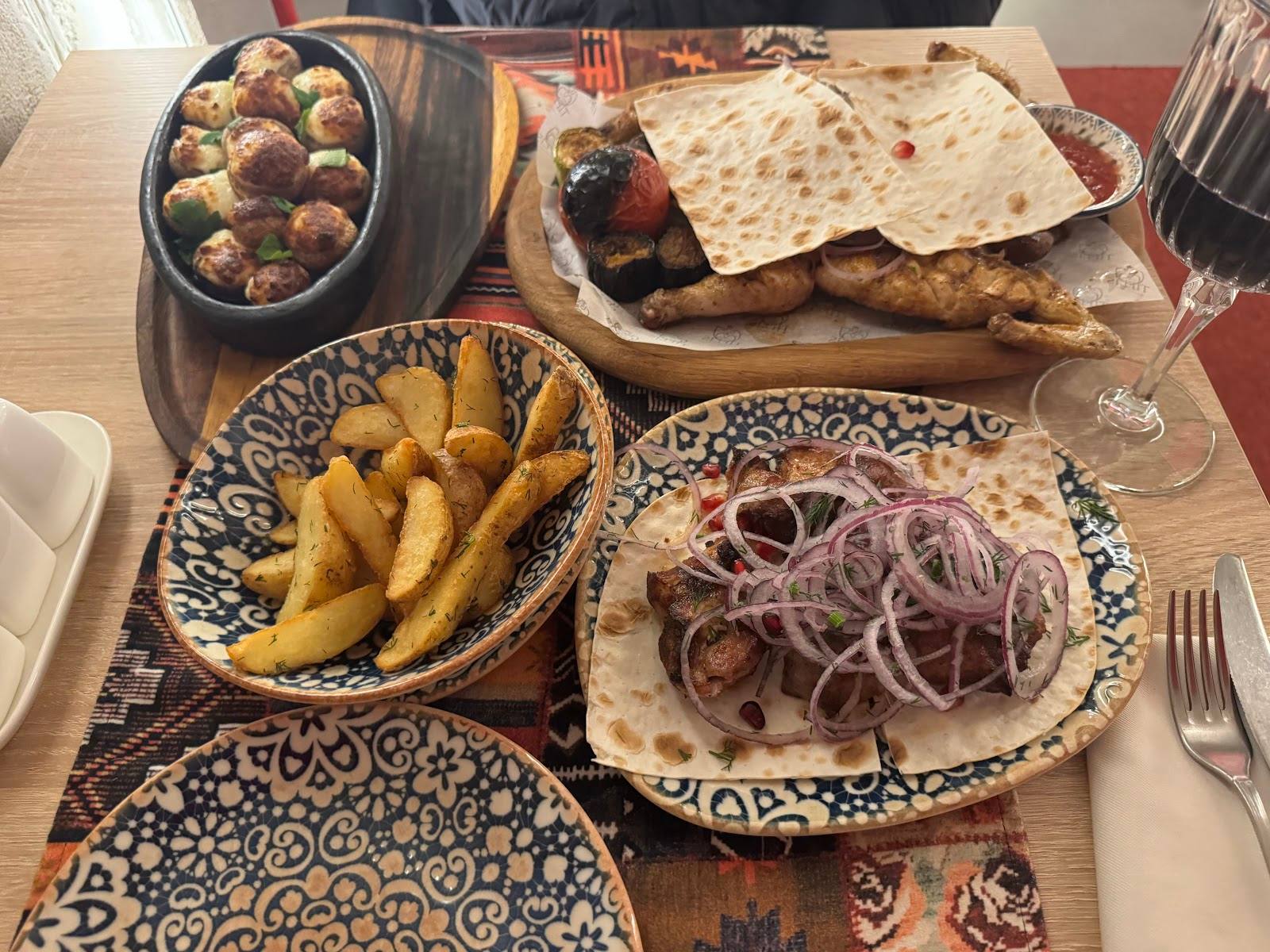 Table spread of grilled meat, fries, and traditional appetizers at restaurant