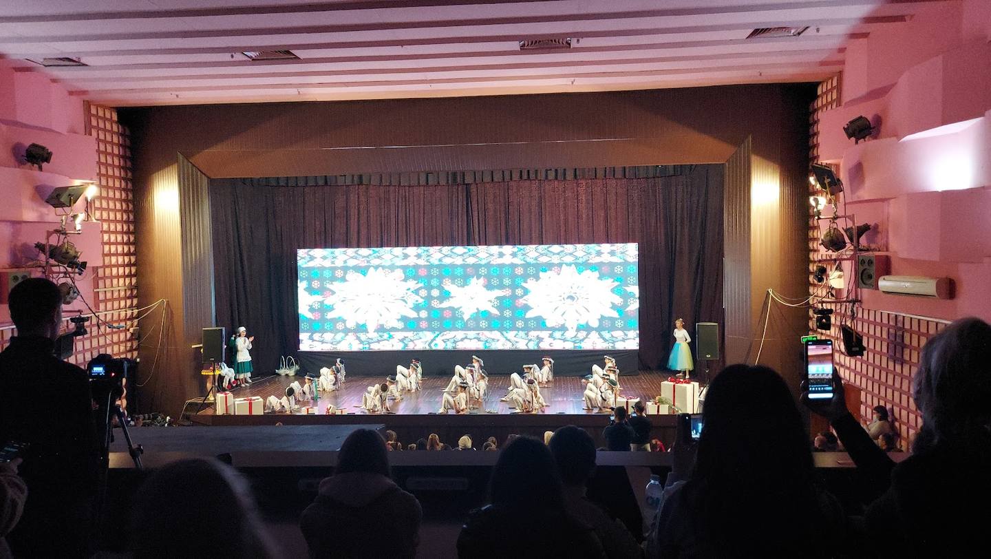Event venue with stage, large projection screen, and audience during live performance or presentation.