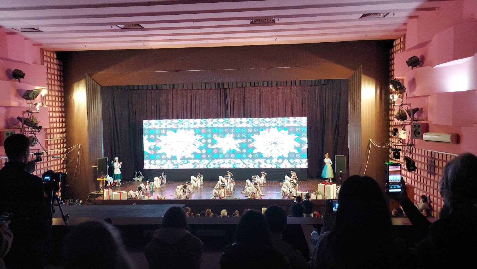 Event venue with stage, large projection screen, and audience during live performance or presentation.