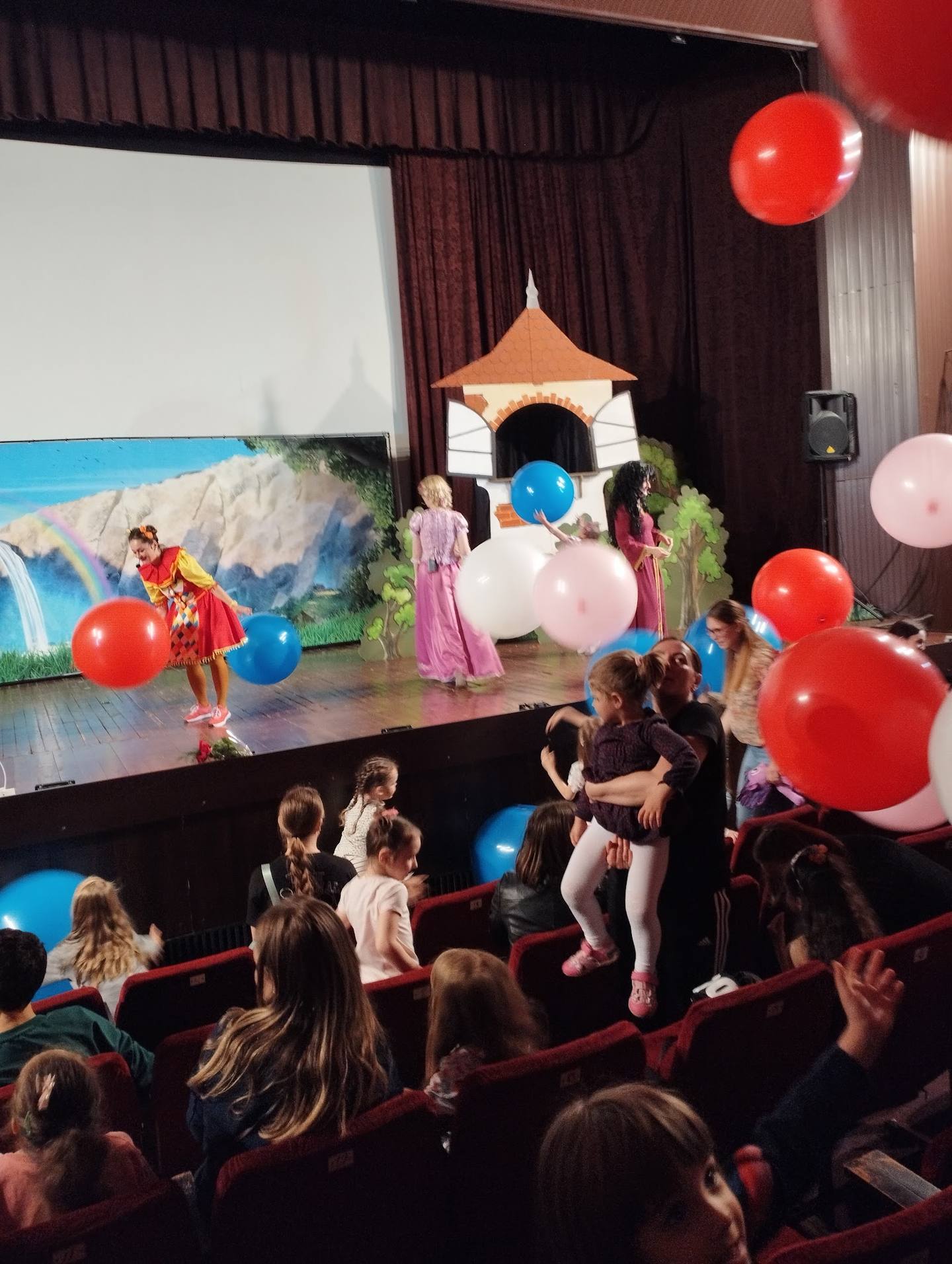 Children's interactive theater performance with colorful balloons and projection screens
