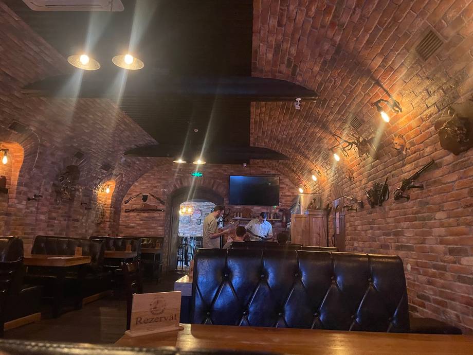 Interior bar space with exposed brick walls, ambient lighting, and blue leather seating