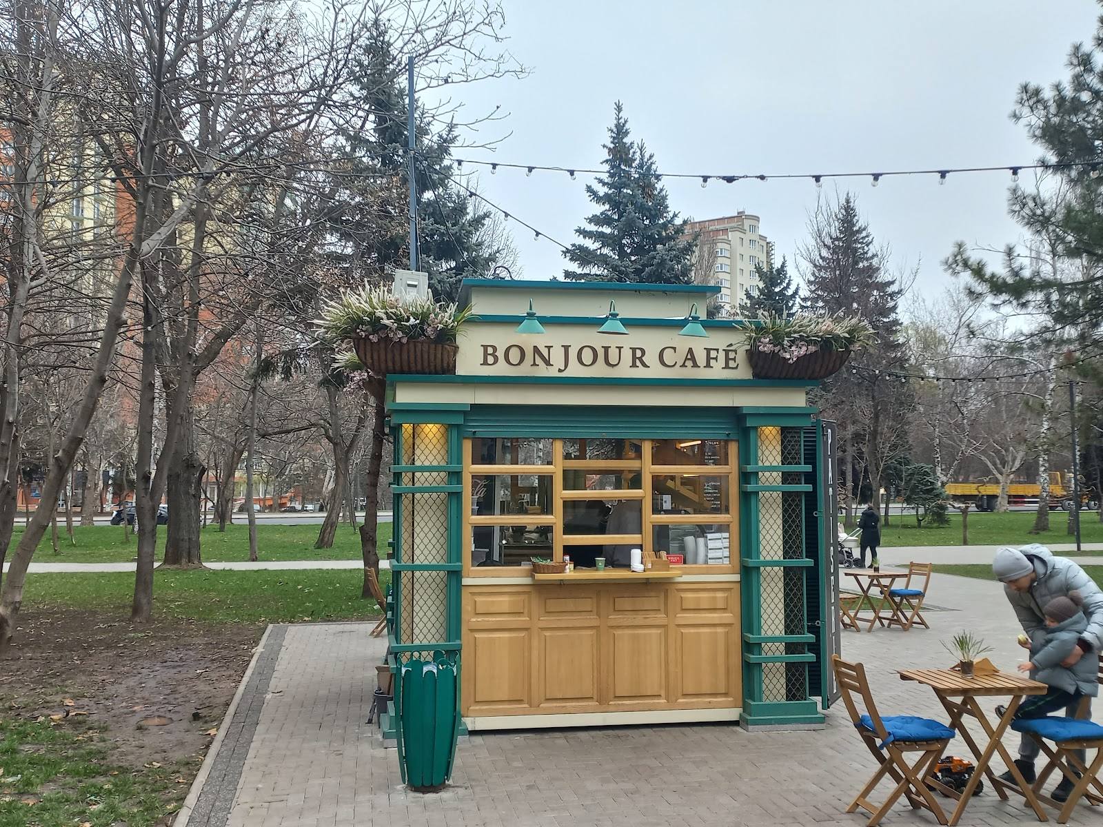Bonjour Café kiosk in park with green facade and wooden serving window