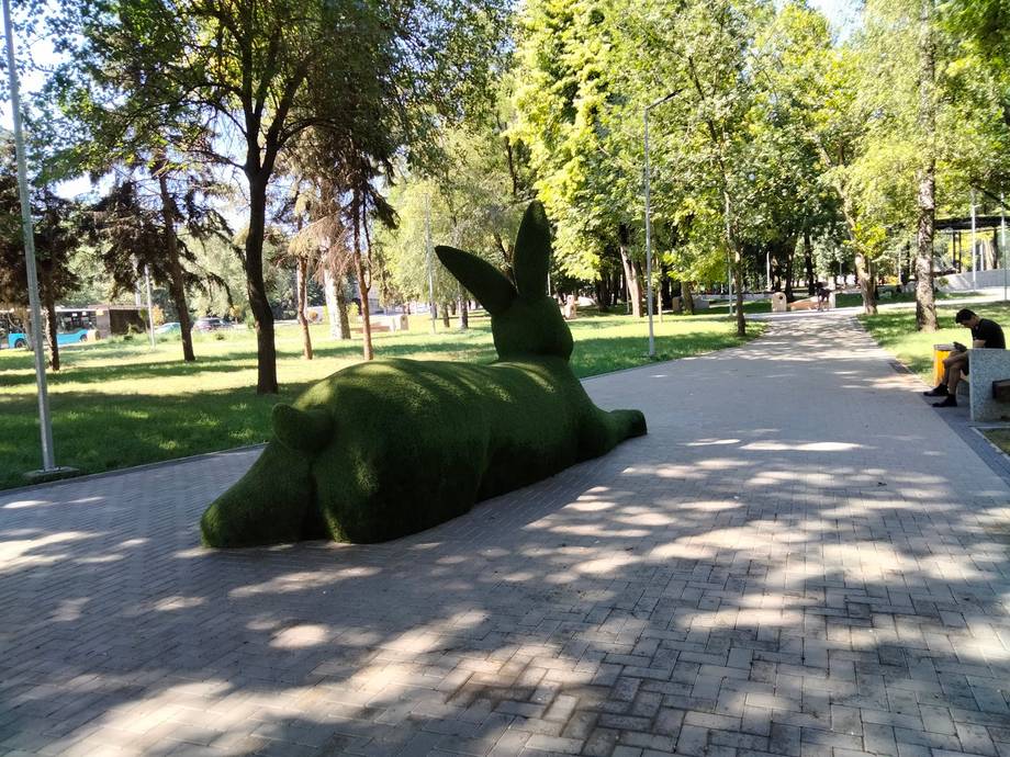 Public park with topiary sculpture and tree-lined pathways