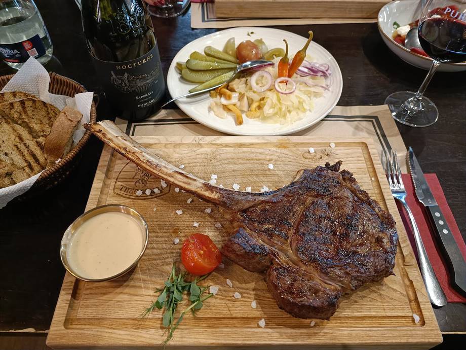 Grilled steak with sides and wine service on wooden board