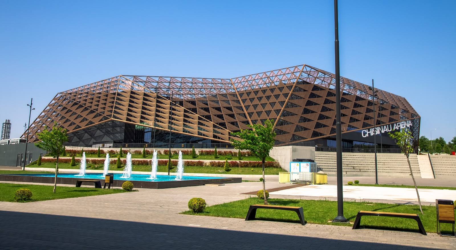 Modern arena exterior with distinctive latticed dome design and landscaped grounds