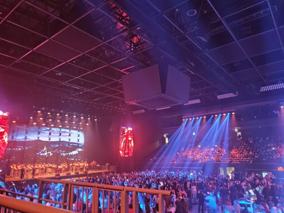 Large concert hall with stage lighting and crowd during live performance
