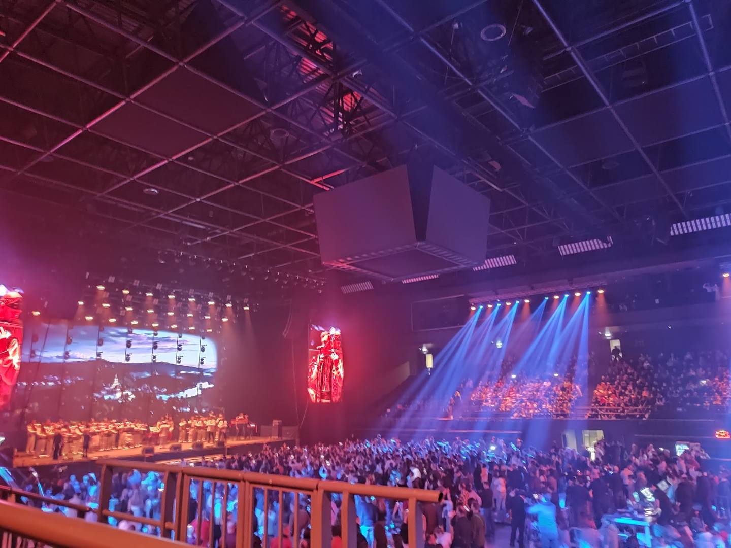 Large concert hall with stage lighting and crowd during live performance