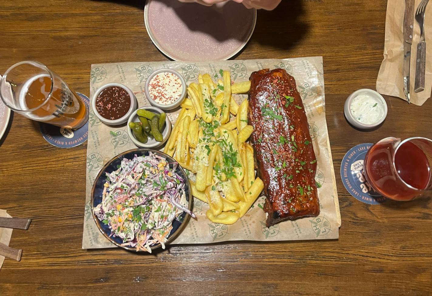 Charcuterie and salad board with sides and beverages on wooden table